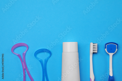 Tongue cleaners  toothbrush and paste on blue background  flat lay. Space for text
