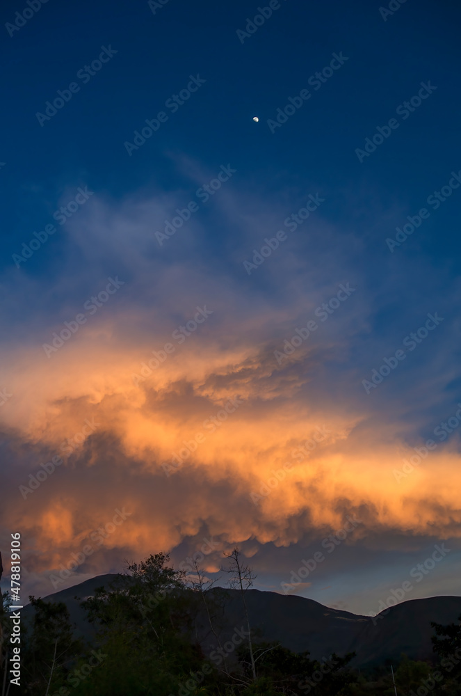 A little crescent moon hangs up over a huge mammatus cumulus cloud at sunset near the colonial town of Villa de Leyva in central Colombia.