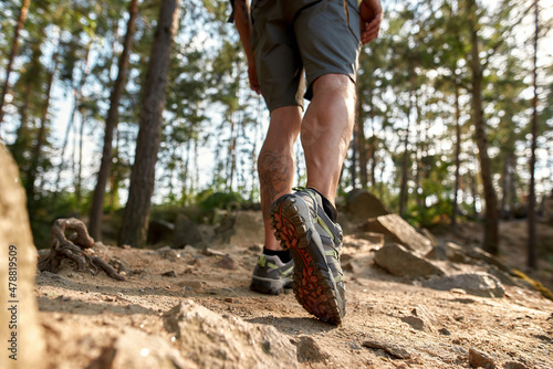 Muscular legs of caucasian man wearing trekking boots