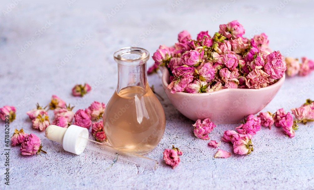 Rose essential oil in glass bottle and pink rose flowers . Rose water Rose essential oil in glass bottle and pink rose flowers . Rose water