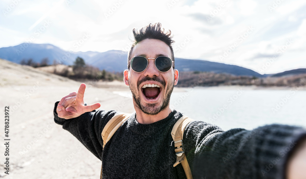 Young man taking selfie portrait outside - Happy guy smiling at camera outdoors - Happy lifestyle and technology concept