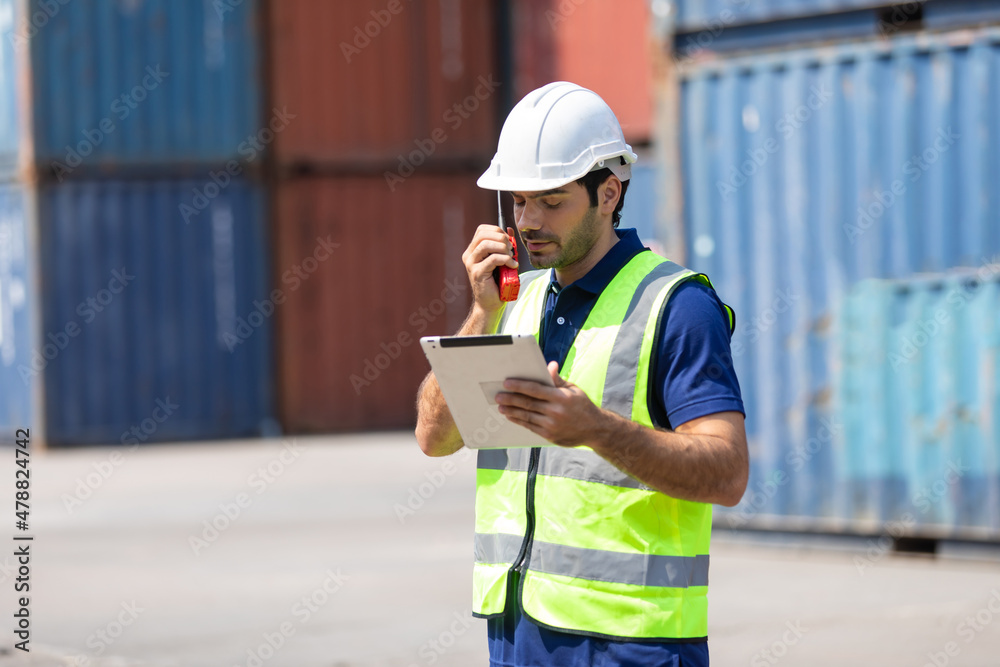 Obraz premium foreman manager working through a radio communication with the workers in the container yard at port of import and export goods.