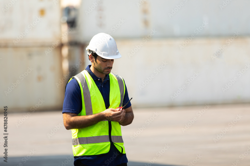 foreman manager working through a radio communication with the workers in the container yard at port of import and export goods. foreman manager working through a radio communication with the workers in the container yard at port of import and export goods.