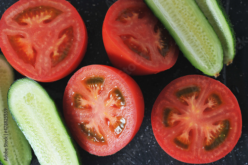 red tomatoes and cucumbers cut into halves - top view © Deno