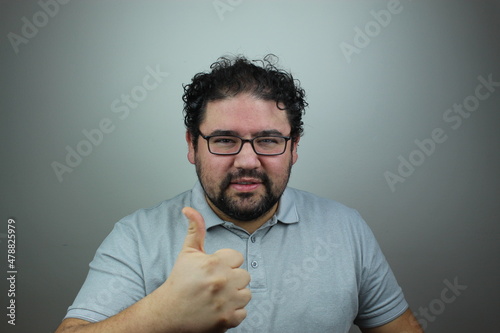young man with glasses makes thumb up sign