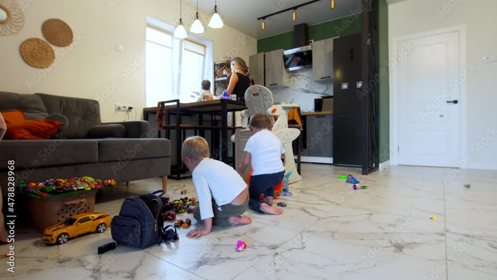 Timelapse: Korean family: parents with one year old son in the kitchen, the 4 years old son is playing small cars on the floor with his friend. Domestic environment. Light room Timelapse: Korean family: parents with one year old son in the kitchen, the 4 years old son is playing small cars on the floor with his friend. Domestic environment. Light room