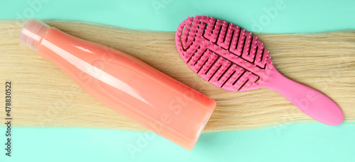 Female hair with shampoo and hairbrush on mint background