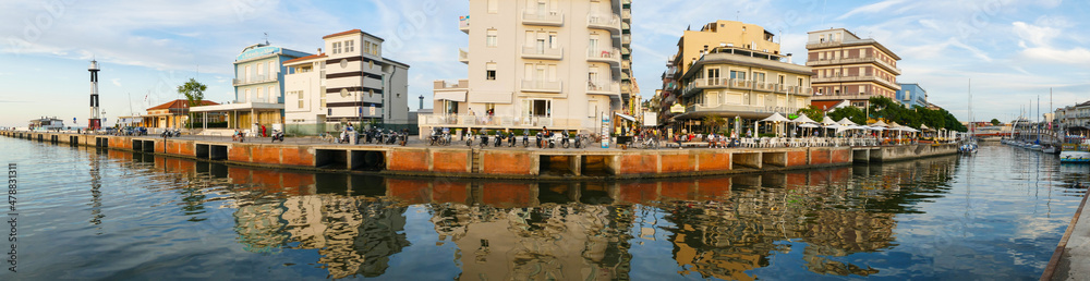 Extra wide panorama of The canal that divides Cattolica from Gabicce with the buildings that are reflected in the water at sunset