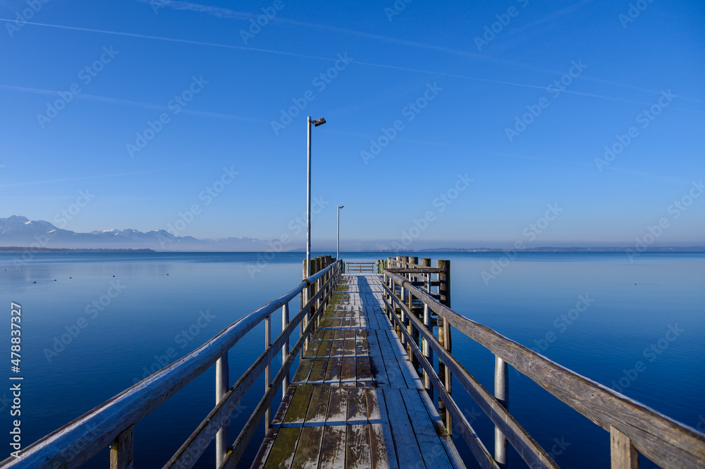 Fototapeta premium Calm Chiemsee in winter with ducks mountains and clear sky fog