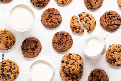 Fresh cookies with chocolate chips and milk pattern on white background.