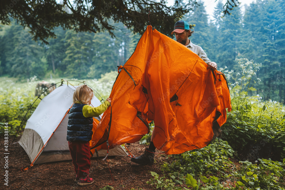 Child and father are setting camping tent family vacations travel hiking outdoor in forest adventure trip healthy lifestyle - obrazy, fototapety, plakaty 