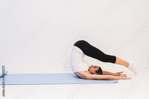 Young woman in yoga class doing shoulder stand