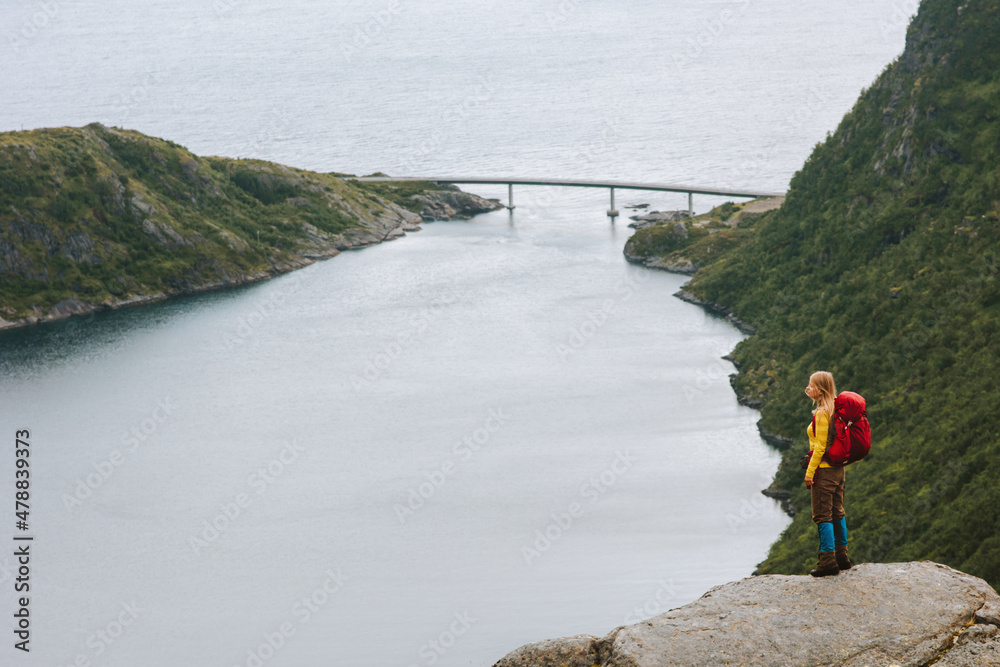 Traveler woman hiking outdoor in Norway traveling solo standing on cliff backpacking tour healthy lifestyle adventure summer vacations