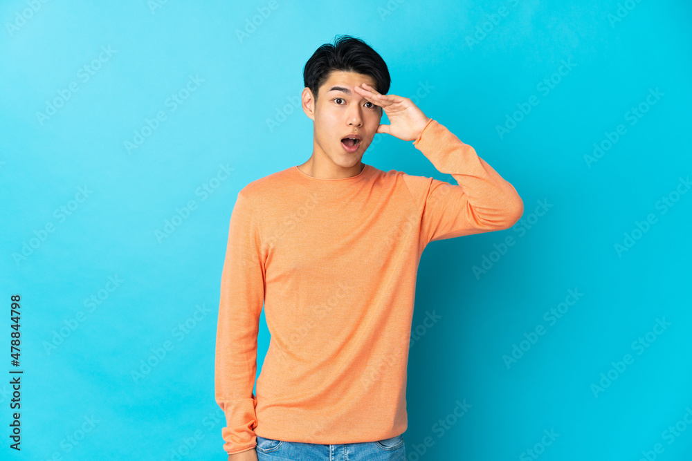 Young Chinese man isolated on blue background has realized something and intending the solution Young Chinese man isolated on blue background has realized something and intending the solution