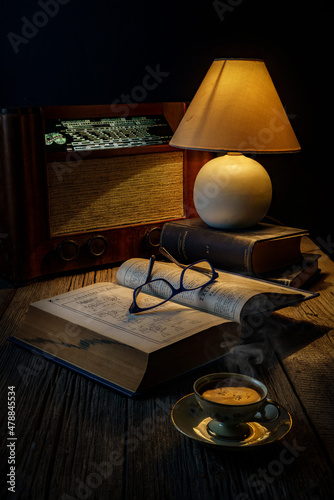 Traditional coffee in a vintage cup. Old radio with vacuum tubes, old electronics book, reading glasses.
Atmosphere of warm low light
