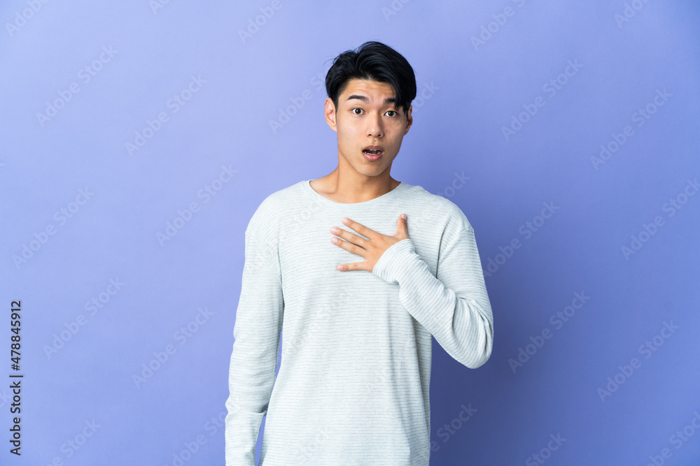 Young Chinese man isolated on purple background surprised and shocked while looking right Young Chinese man isolated on purple background surprised and shocked while looking right