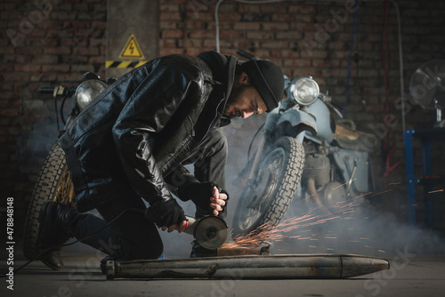 Man in the leather jacket works in the motorbike workshop concept.