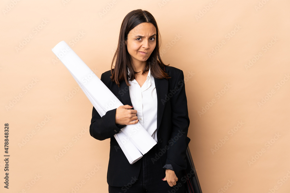Young architect woman holding blueprints over isolated background having doubts Young architect woman holding blueprints over isolated background having doubts