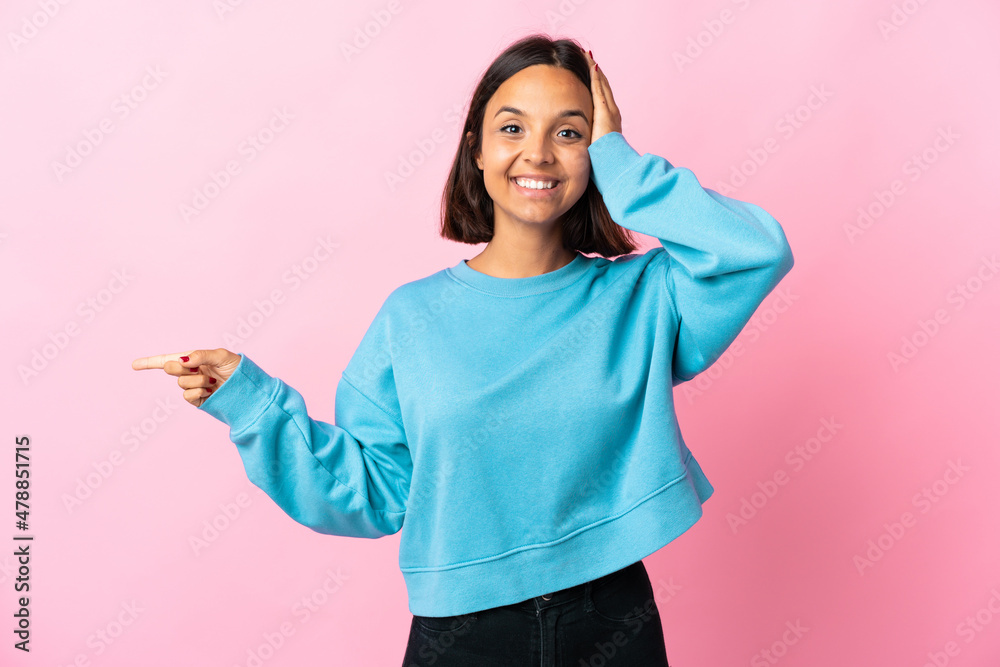 Young latin woman isolated on pink background surprised and pointing finger to the side Young latin woman isolated on pink background surprised and pointing finger to the side
