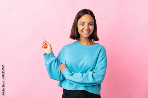 Young latin woman isolated on pink background happy and pointing up