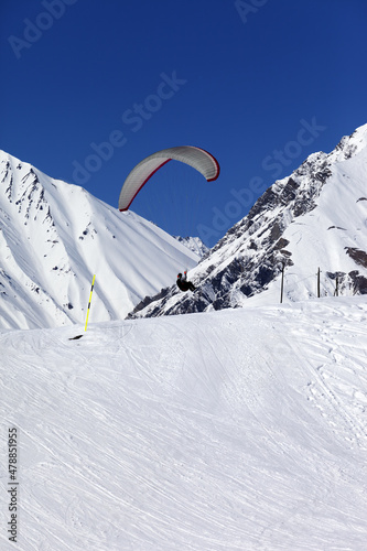 Skydiver landing on ski slope at nice sun day