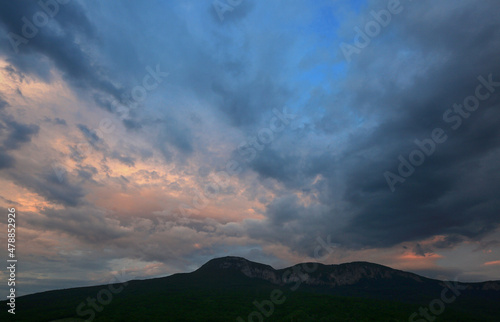 Beautiful clouds over mountains in the evening sky © yanakoroleva27
