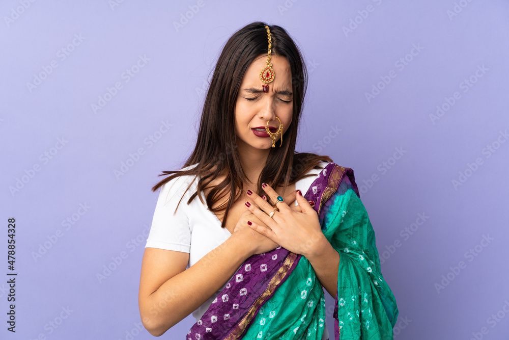 Young Indian woman isolated on purple background having a pain in the heart Young Indian woman isolated on purple background having a pain in the heart