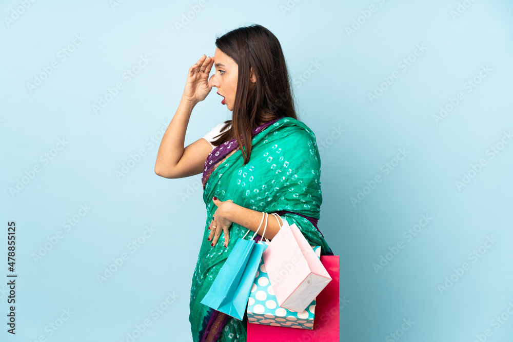 Young Indian woman with shopping bags with surprise expression while looking side Young Indian woman with shopping bags with surprise expression while looking side