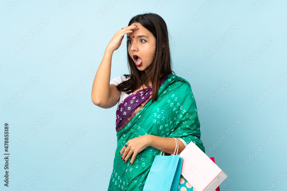 Young Indian woman with shopping bags doing surprise gesture while looking to the side Young Indian woman with shopping bags doing surprise gesture while looking to the side