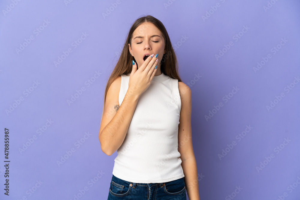 Young Lithuanian woman isolated on purple background yawning and covering wide open mouth with hand Young Lithuanian woman isolated on purple background yawning and covering wide open mouth with hand