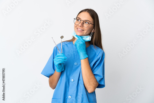 Lithuanian woman dentist holding tools over isolated background looking up while smiling