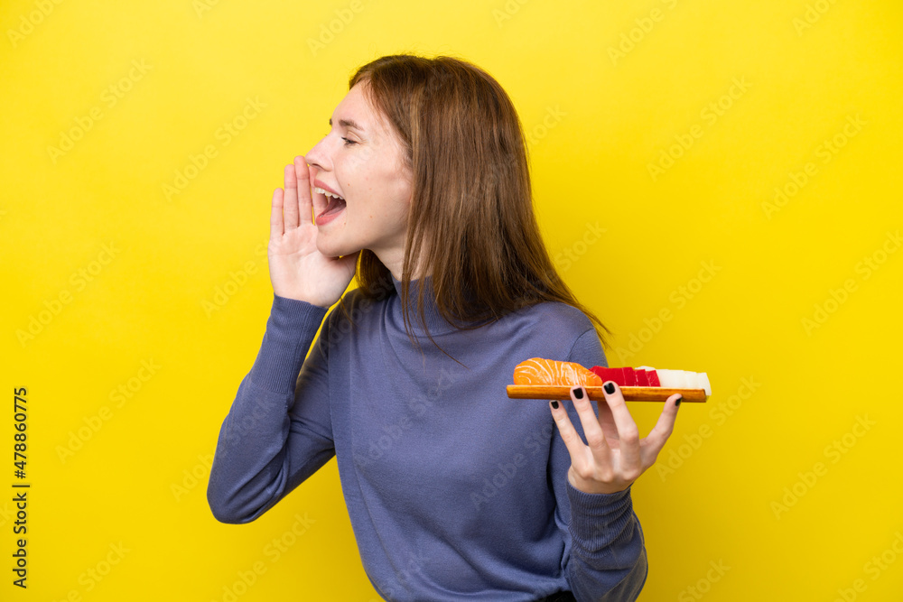 Young English woman holding sashimi isolated on yellow background shouting with mouth wide open to the side