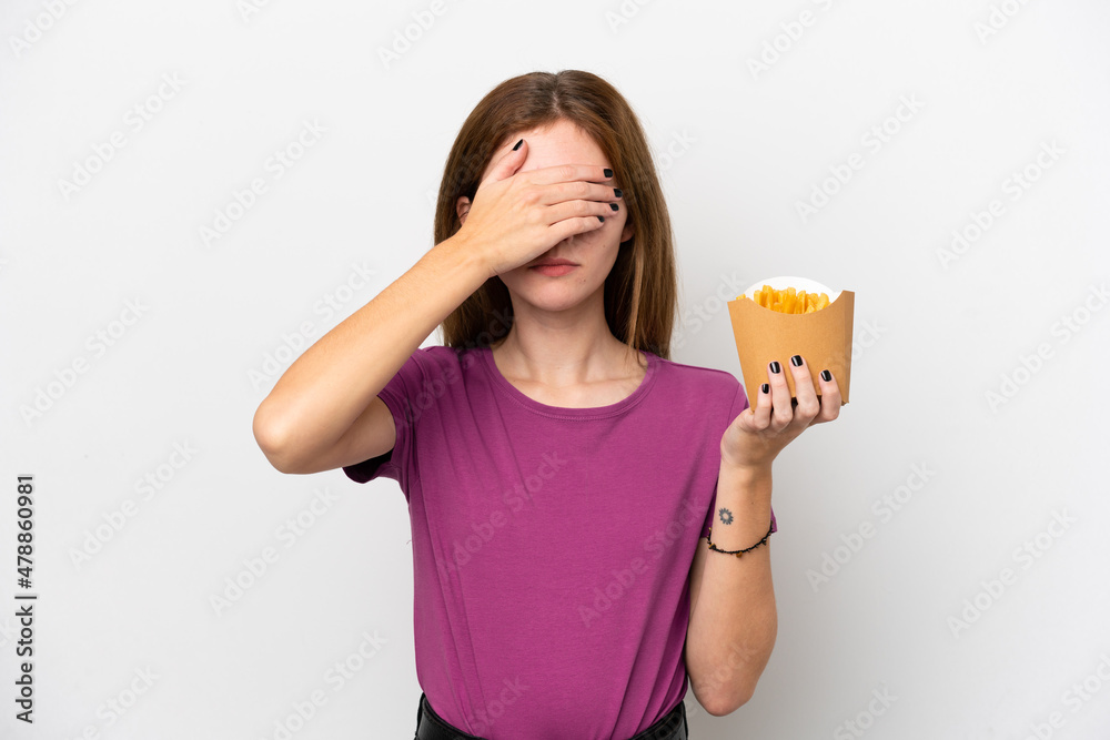 Young English woman holding fried chips isolated on white background covering eyes by hands. Do not want to see something Young English woman holding fried chips isolated on white background covering eyes by hands. Do not want to see something