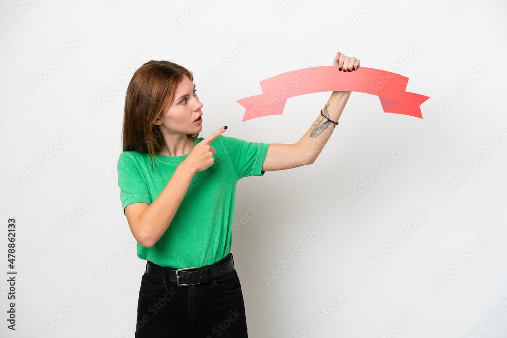 Young English woman isolated on white background holding an empty placard and pointing it Young English woman isolated on white background holding an empty placard and pointing it