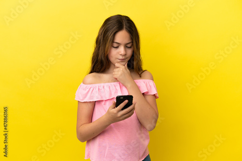 Little caucasian girl isolated on yellow background thinking and sending a message