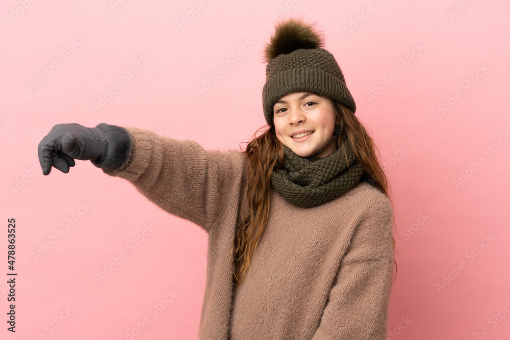 Little girl with winter hat isolated on pink background giving a thumbs up gesture Little girl with winter hat isolated on pink background giving a thumbs up gesture