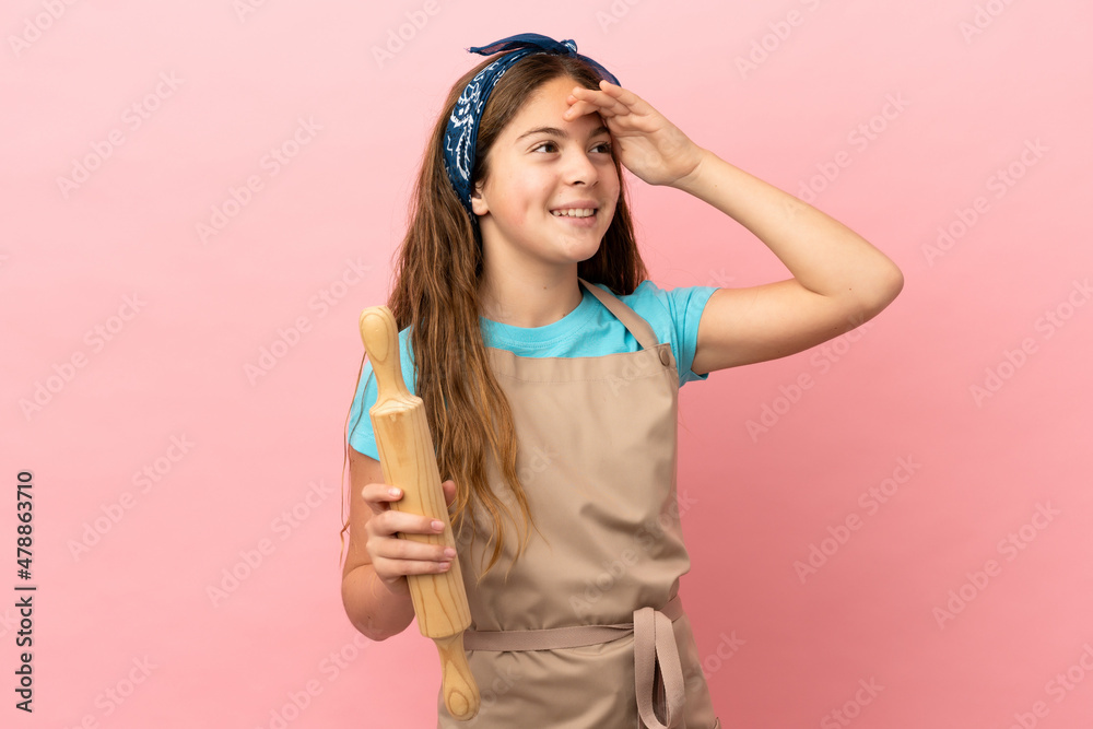 Little caucasian girl holding a rolling pin isolated on pink background smiling a lot Little caucasian girl holding a rolling pin isolated on pink background smiling a lot