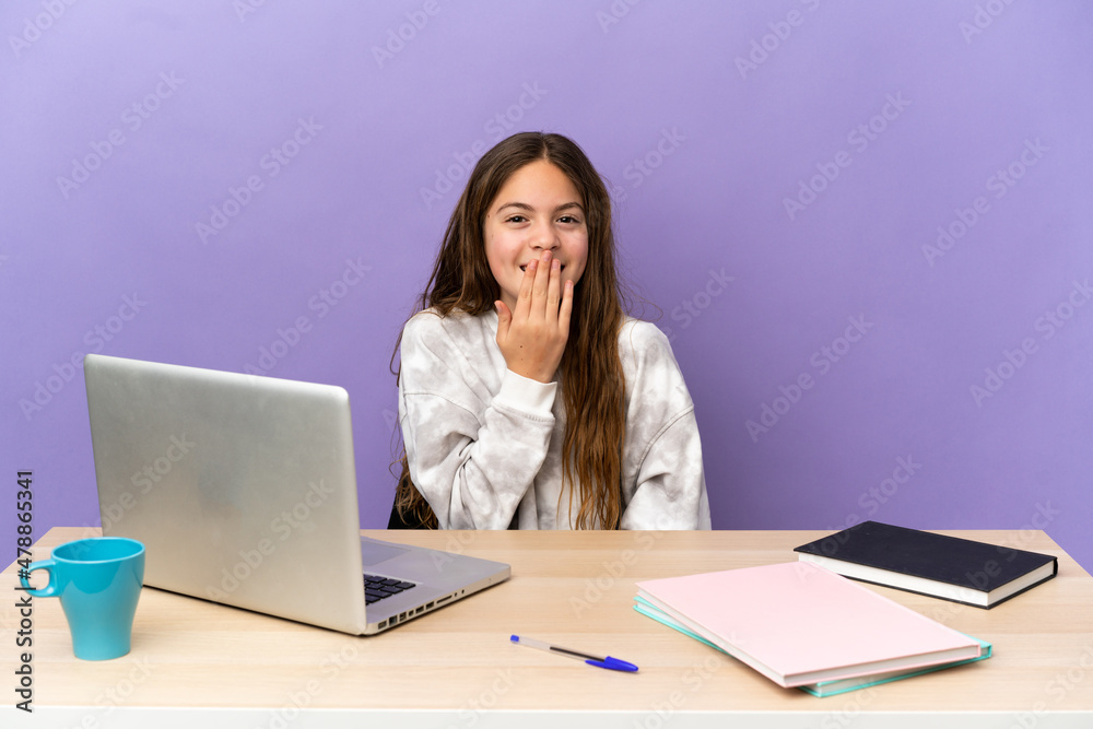 Little student girl in a workplace with a laptop isolated on purple background happy and smiling covering mouth with hand Little student girl in a workplace with a laptop isolated on purple background happy and smiling covering mouth with hand