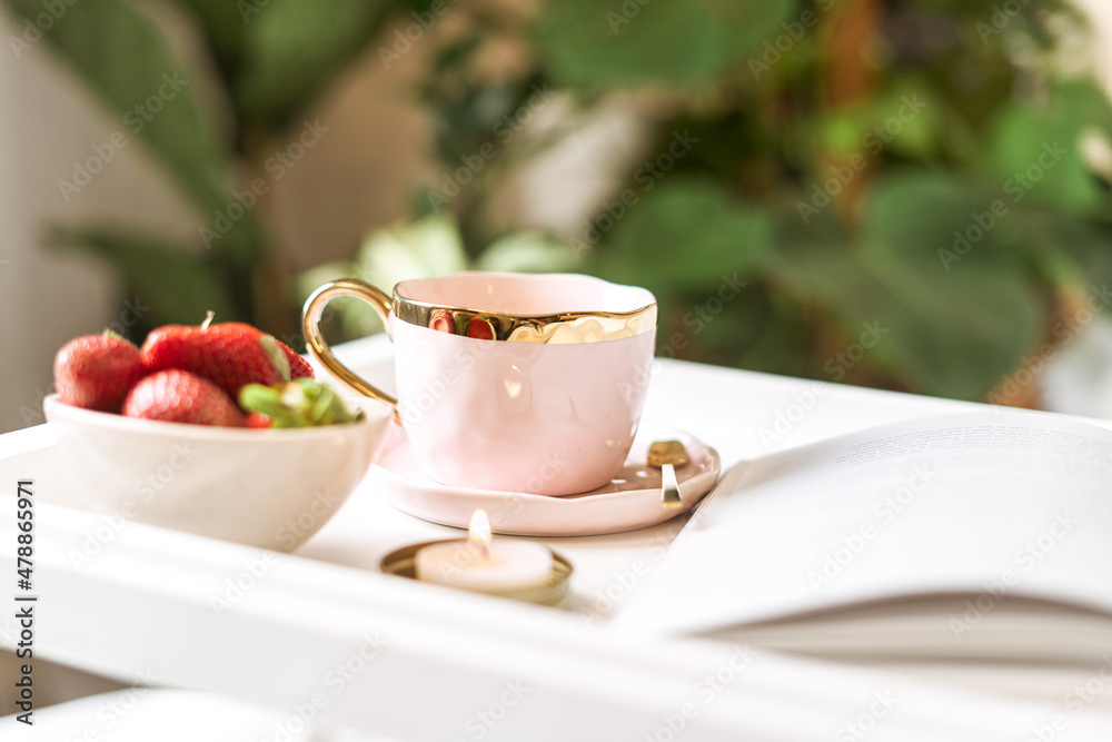 Breakfast in bed. Heart shaped white plate with fresh strawberries, cup of coffee, book and plants flowers. Still life composition. Mother, Valentine day concept. Breakfast in bed. Heart shaped white plate with fresh strawberries, cup of coffee, book and plants flowers. Still life composition. Mother, Valentine day concept.