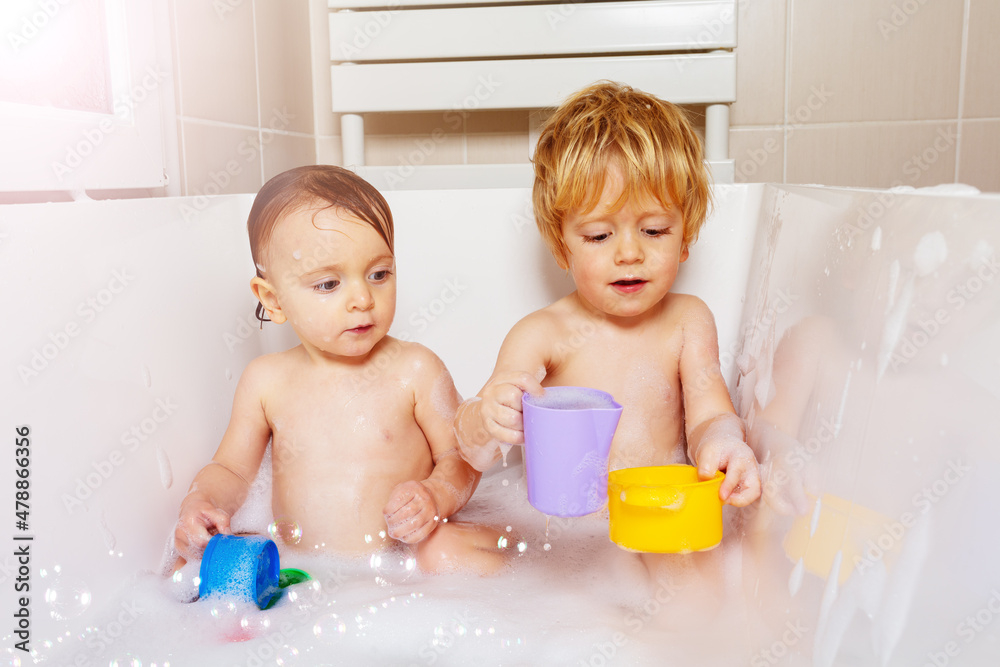 Babies play with toys and soap in a bath together Babies play with toys and soap in a bath together