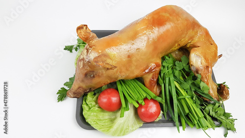 there is a baked piglet on the tray, decorated with vegetables. pig carcass baked in the oven photo