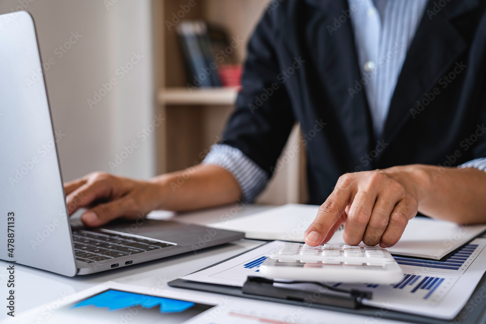 Close-up calculator to calculate the company's financial results On the wooden table in the office and business work background, tax, accounting, statistics, and analytical research concept Close-up calculator to calculate the company's financial results On the wooden table in the office and business work background, tax, accounting, statistics, and analytical research concept