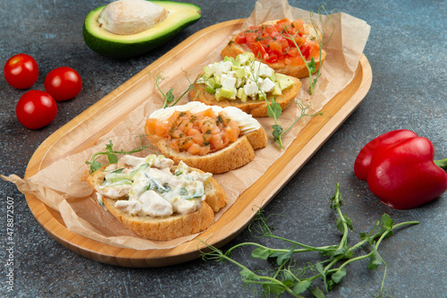Assorted bruschettes on a wooden plate.