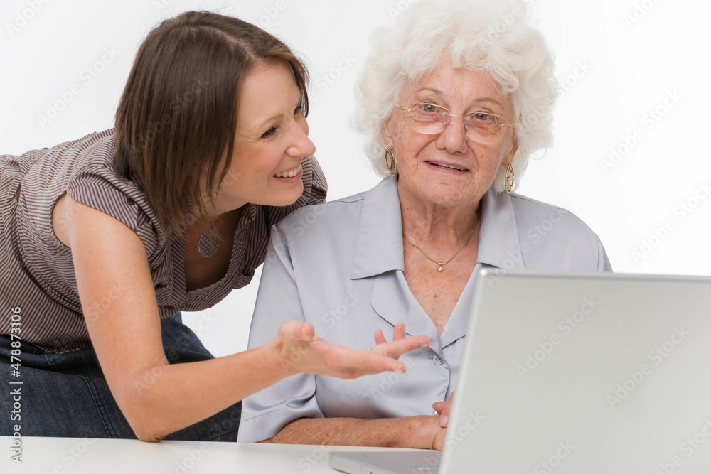 Junge Frau hilft Seniorin bei der Arbeit am Computer Junge Frau hilft Seniorin bei der Arbeit am Computer