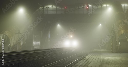 Train arriving at the station in the foggy night photo