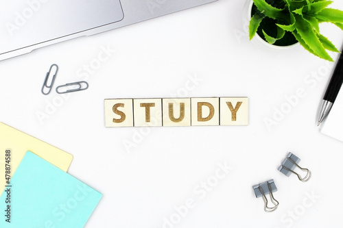Workplace of Student with laptop, pen notes and clips with wood words STUDY on white table top view.