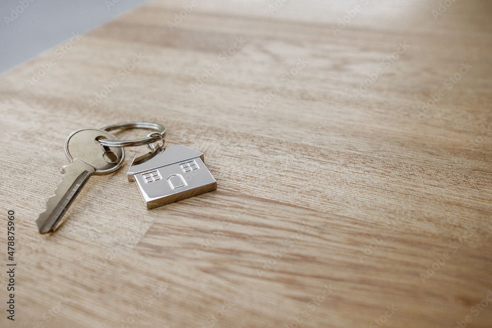 One silver key with a silver key chain in the shape of a house real estate investment One silver key with a silver key chain in the shape of a house real estate investment