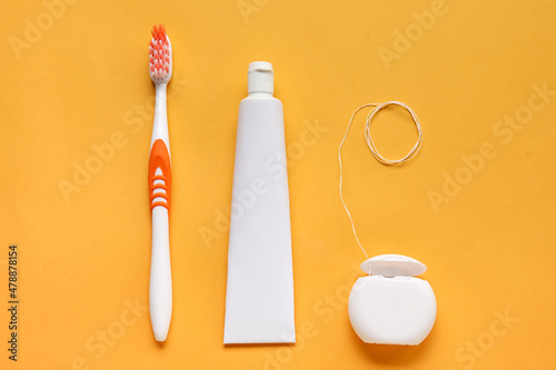 Obraz na plátně Dental floss with tooth paste and brush on orange background