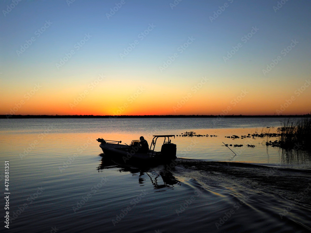 The Silhouette of a Man Heading Out in his Bass Boat Before Sunrise for a Day of Fishing