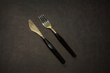 fork and knife gold. Black kitchen utensils placed on a black table. Top view
